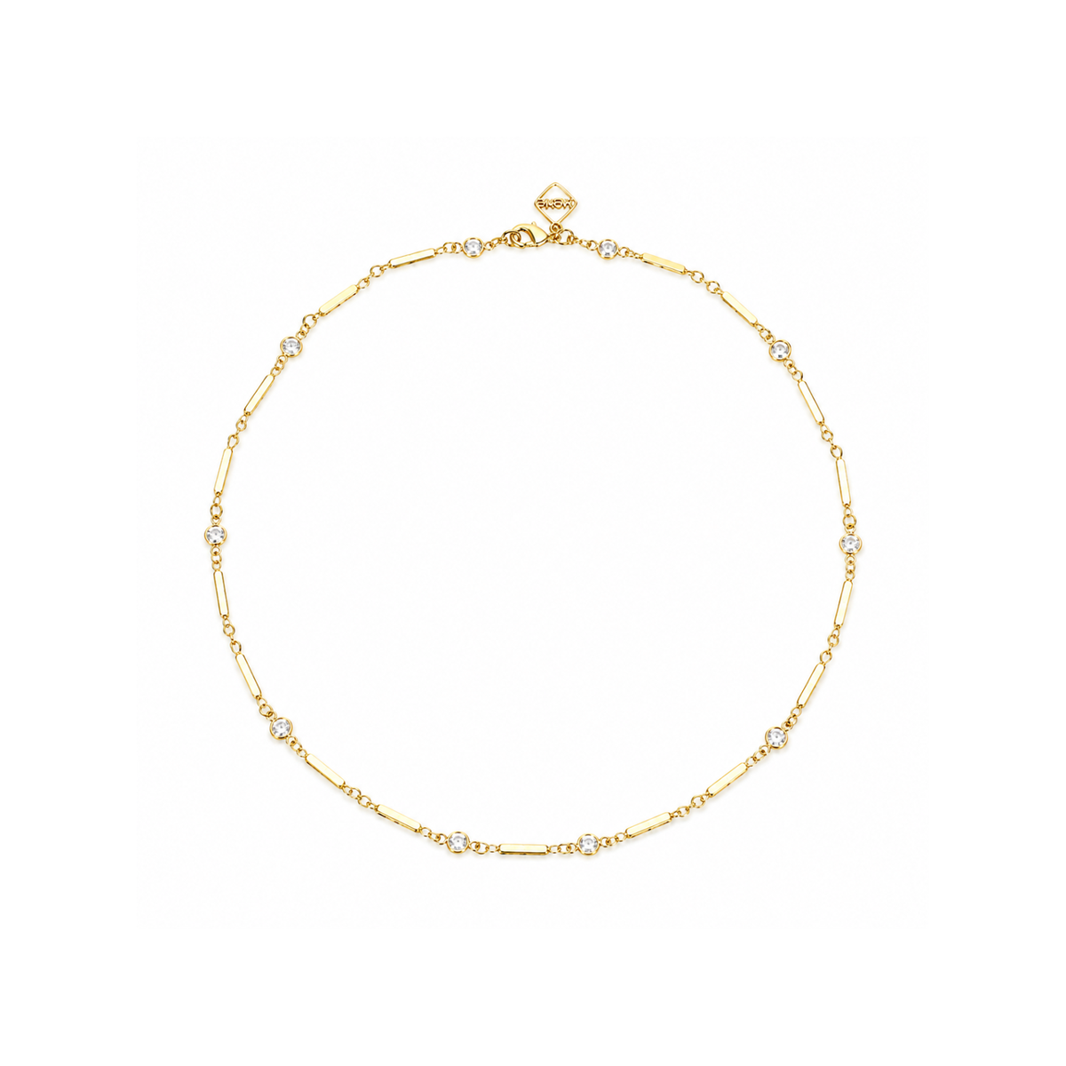 A delicate gold chain necklace with small clear gemstone accents, displayed in a circular shape against a solid white background.