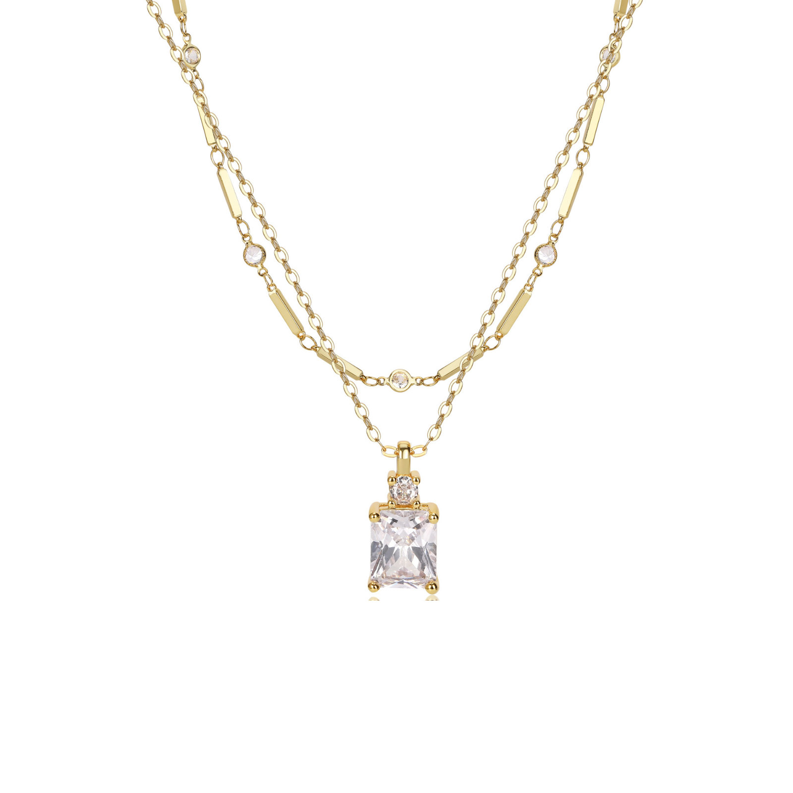 A gold double-strand necklace featuring a rectangular clear gemstone pendant with a bezel setting, accented by small round stones along the chain, shown against a plain white background.