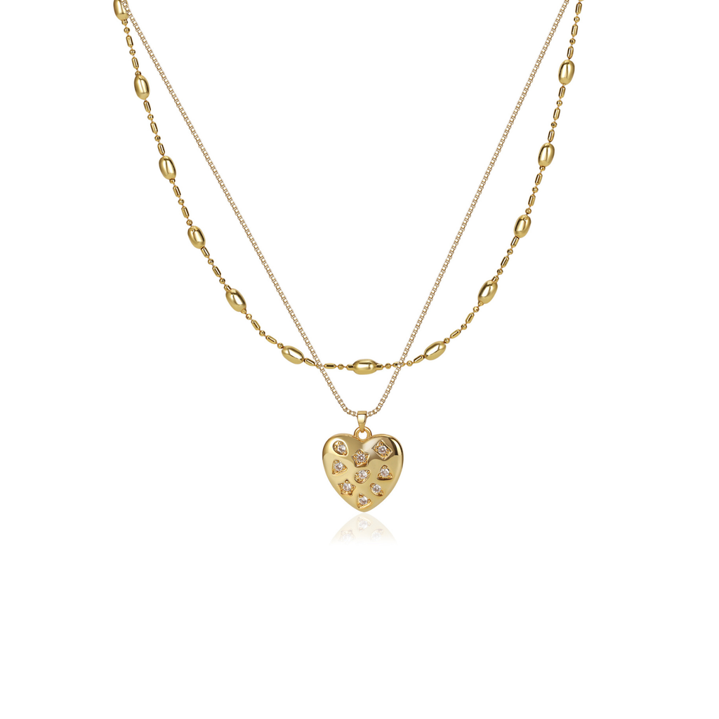 A gold double-layer necklace featuring a textured heart-shaped pendant adorned with small clear crystals, displayed on a clean white background.