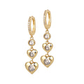 A pair of gold-colored earrings featuring a series of heart-shaped charms with cubic zirconia stones, attached to a hoop closure.